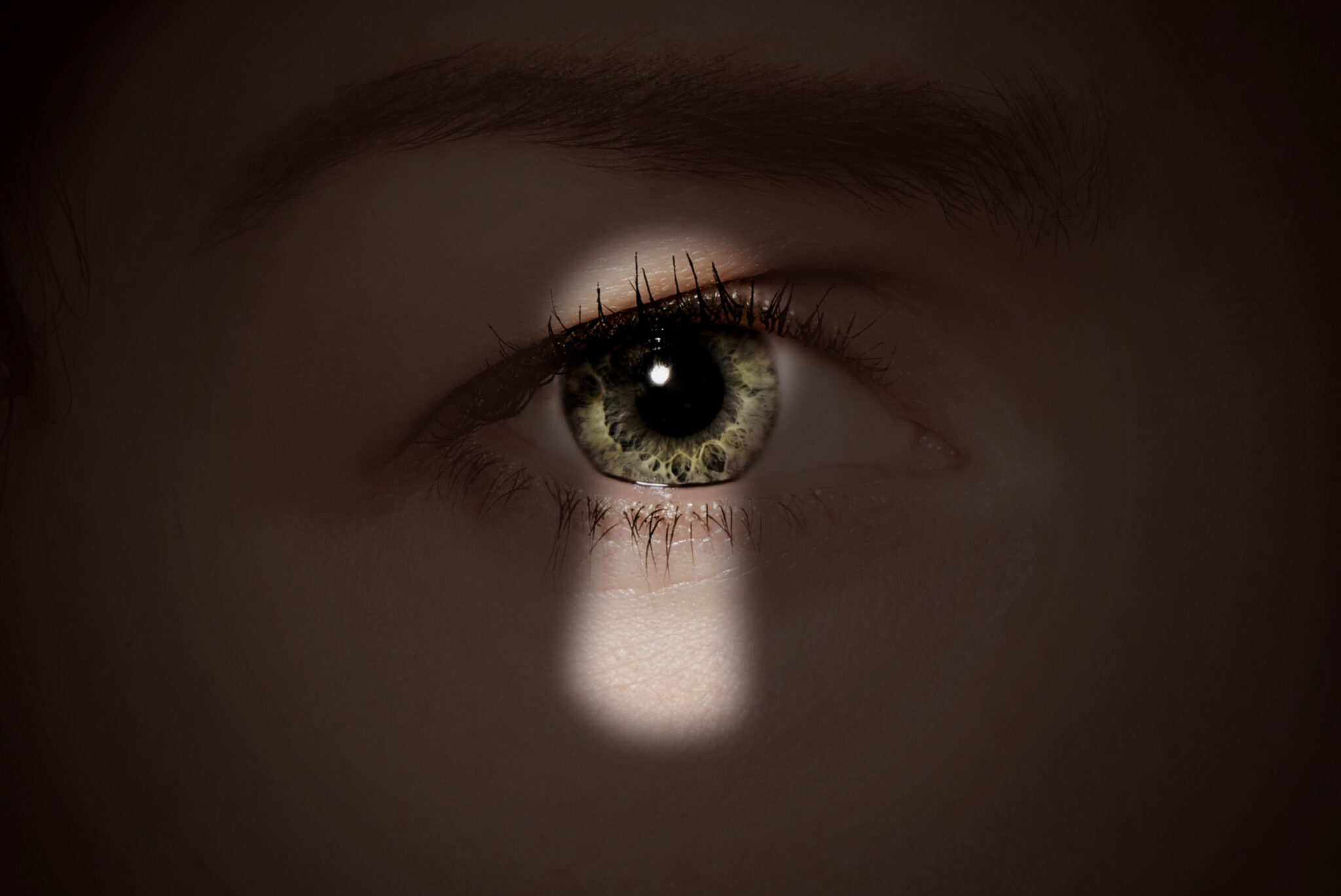 Skuggan av ett nyckelhål mot ett öga.