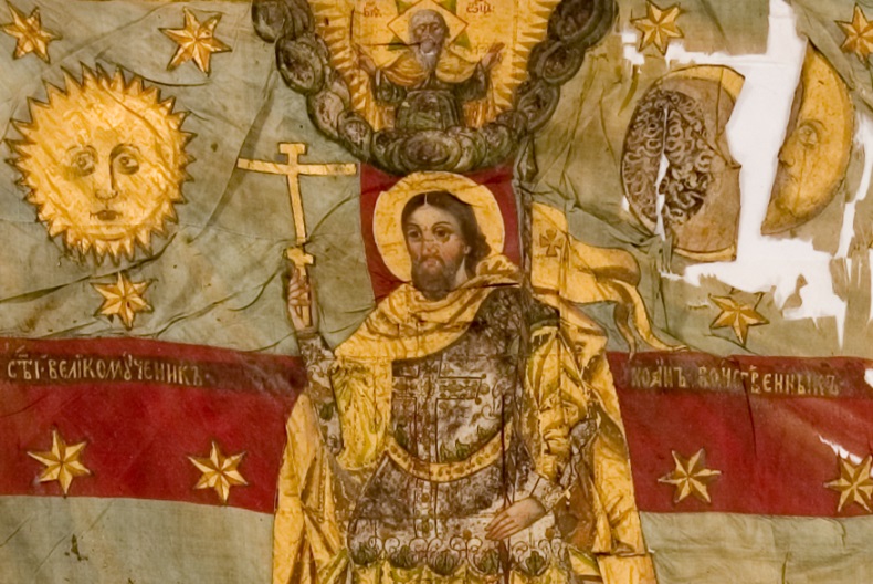 Helgon avbildad på fana i guld, rött, beige och brunt.