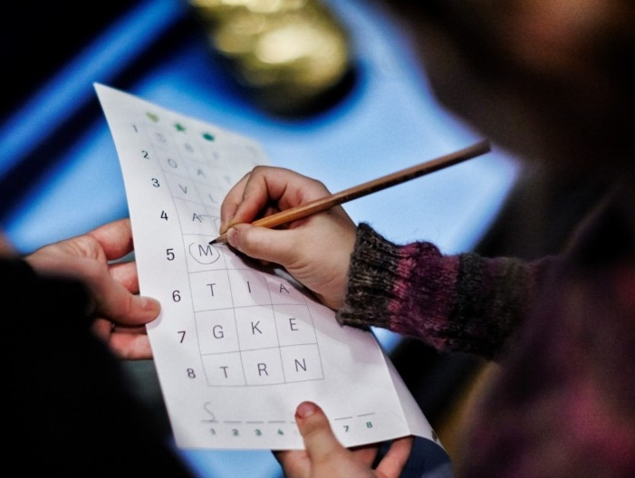 Ett barn löser kluriga uppgifter och ringar in en bokstav på ett papper.