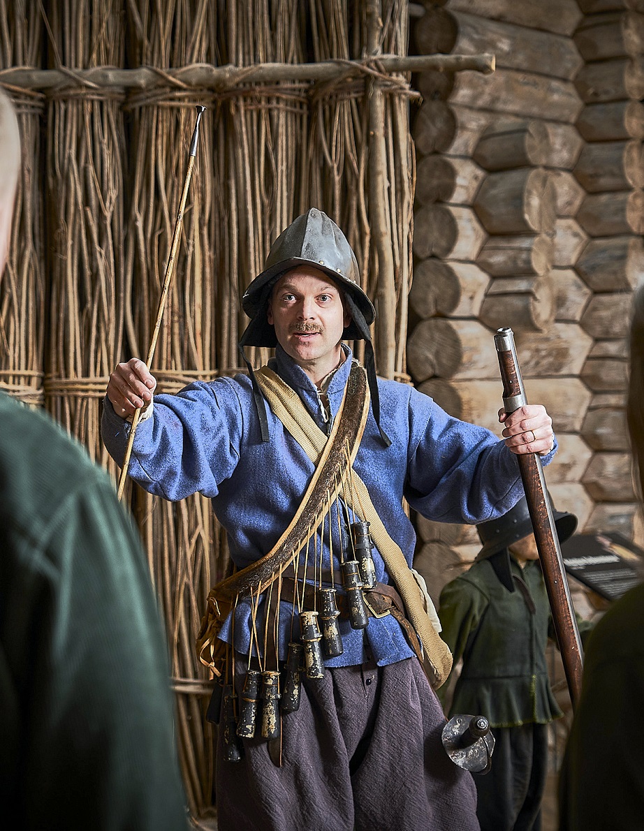 En person utför visning på museet iförd tidstypiska kläder för stormaktstiden.