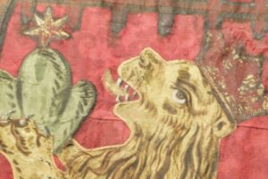 En närbild av fana 03, en bit av ett lejon med öppet gap med röd krona på huvudet