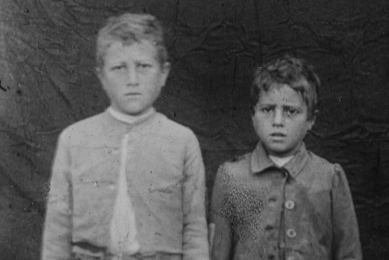 Svartvit bild av två barn med bekymrade miner tittar in i kameran.