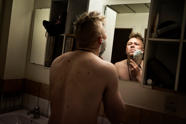 En person står framför en spegel och rakar sig i ett badrum.