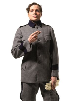 En person iklädd grå uniform, med vita handskar i ena handen och en cigarett i den andra, tittar rakt in i kameran.