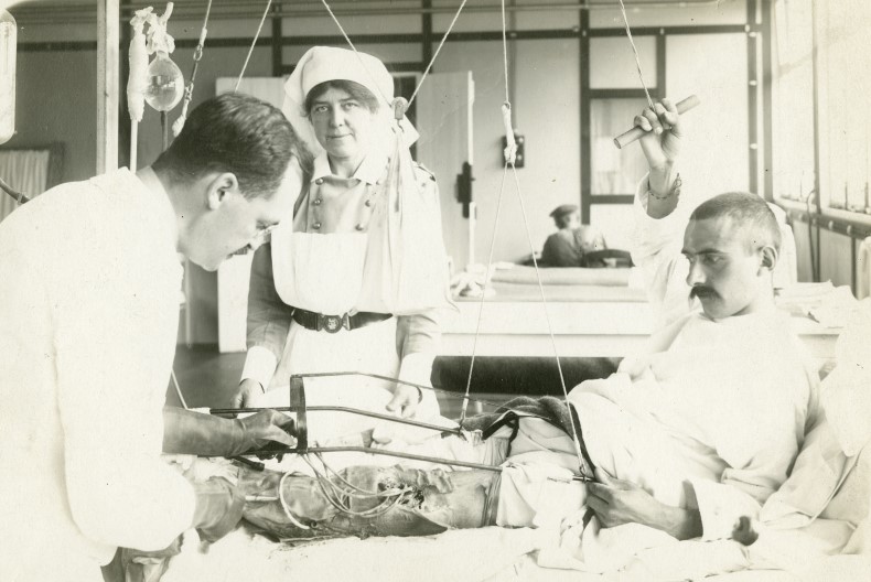 En läkare undersöker benet på en patient i en sjukhussal. Bredvid står en sköterska.