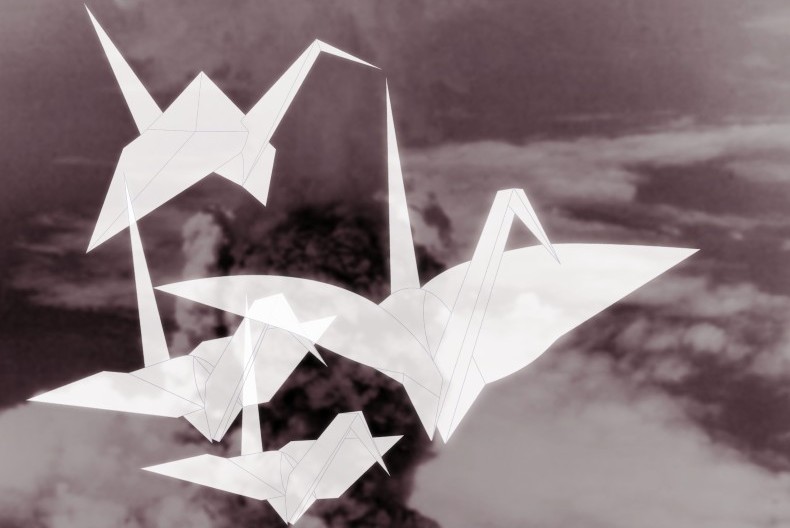 Fyra vita origamitranor flyger över ett svartvitt landskap.