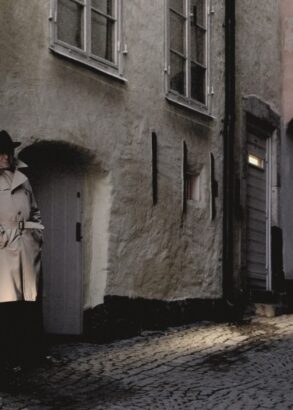 Två personer i en mörk gränd. Iklädda trenchcoats och hattar.