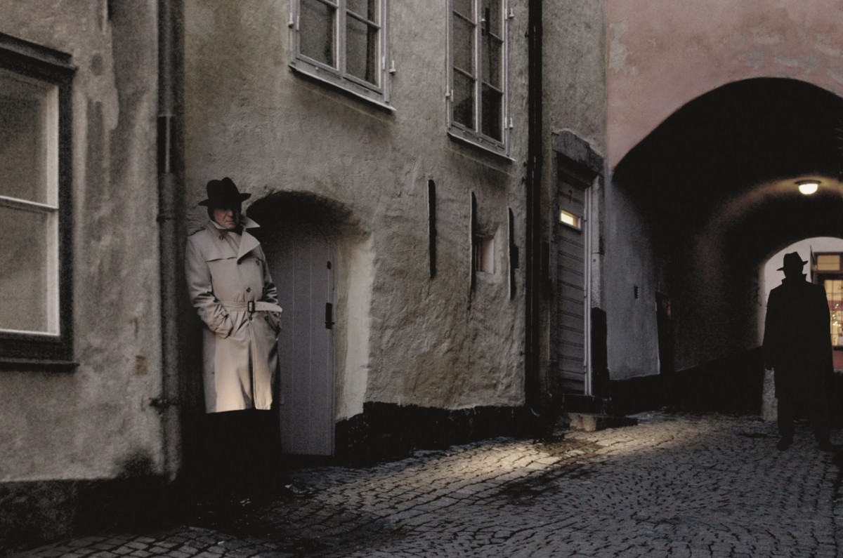 Två personer i en mörk gränd. Iklädda trenchcoats och hattar.