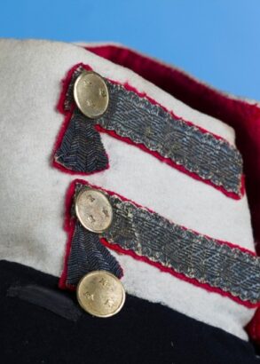 En vit krage på en mörk uniform, den är dekorerad med knappar och kragspeglar.