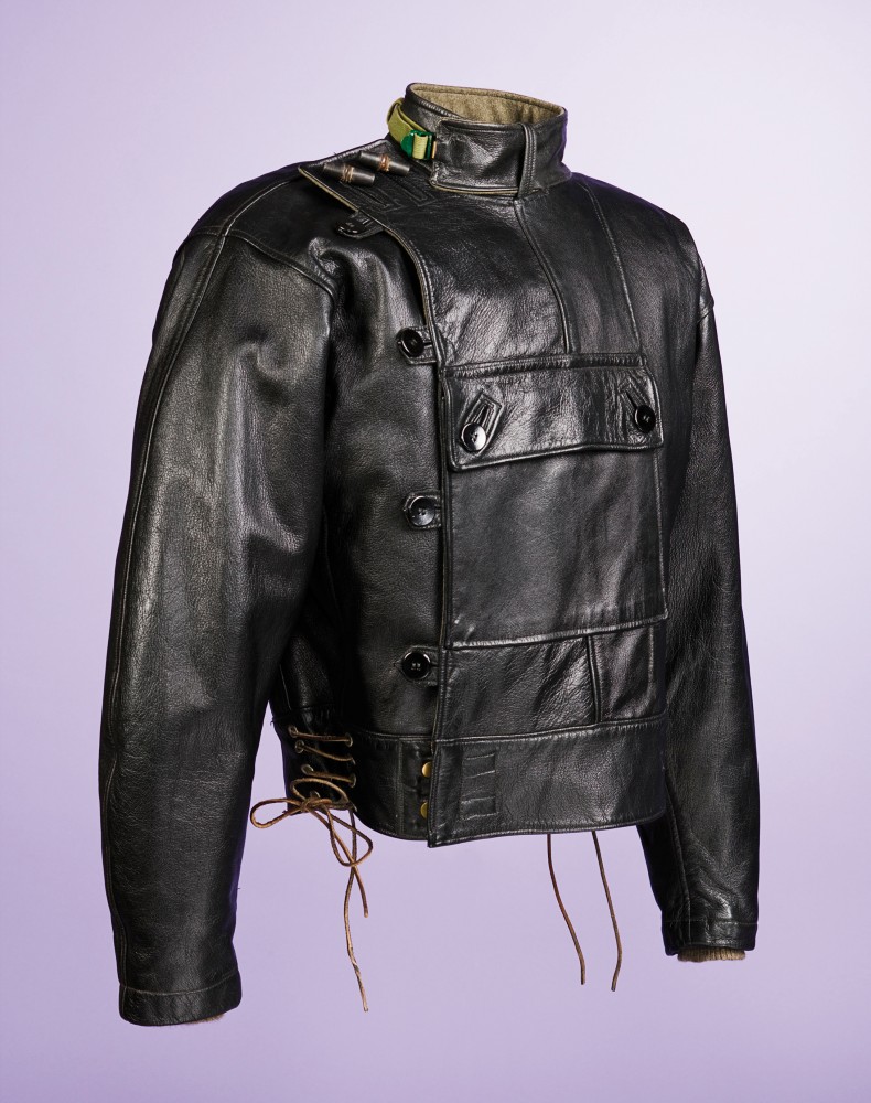 En uniformsliknande svart skinnjacka, mot lila bakgrund.