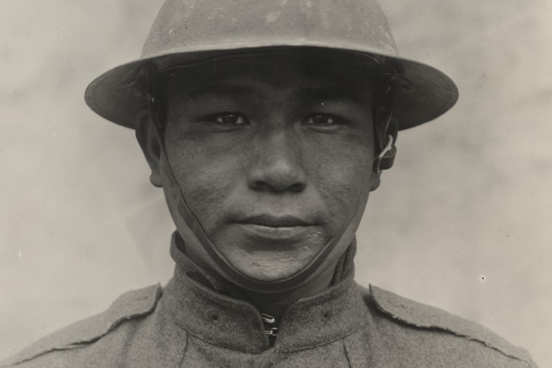 Porträtt av soldat iförd hjälm och uniform. Grå bakgrund.