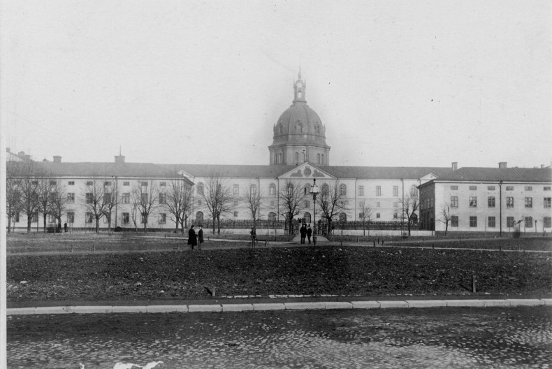 Svartvitt historiskt fotografi av Armémuseum i Stockholm under 1800-talet. Bilden visar den stora byggnaden sedd framifrån, med den centrala kupolen och symmetriska flyglar.