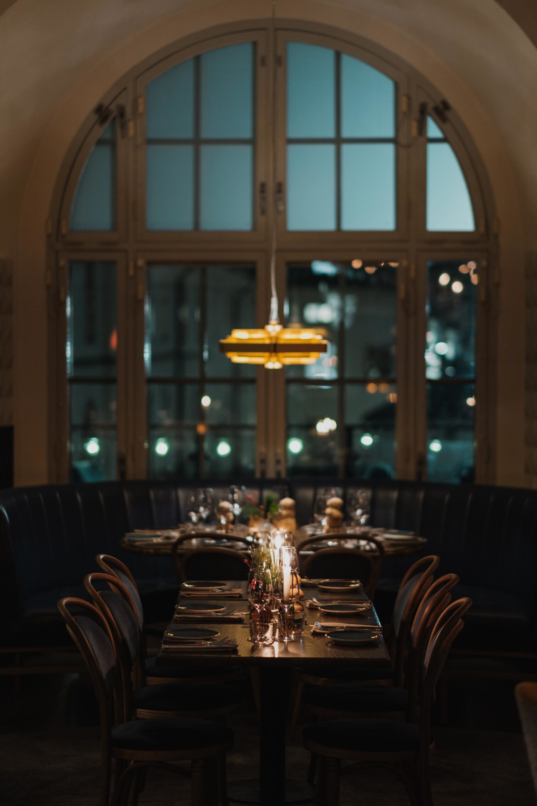Ett dukat bord med stämningsfullt dämpat ljus och ett stort valvfönster i bakgrunden.
